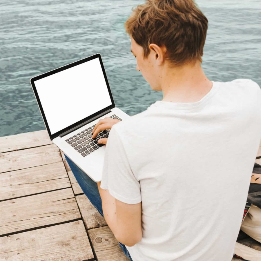 jeune-homme-aide-ordinateur-portable-au-bord-eau